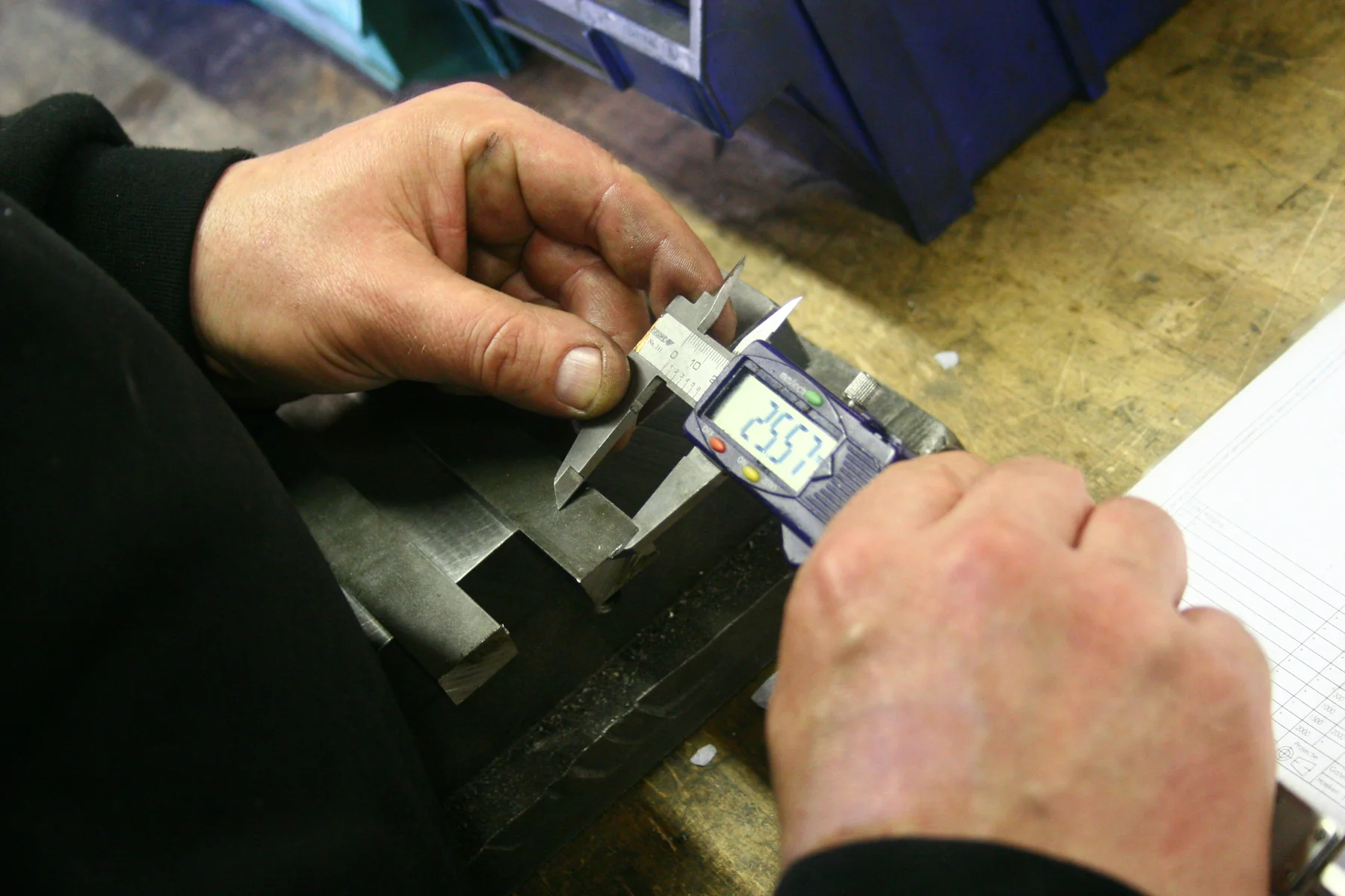 Hands measuring a metal component with a digital caliper